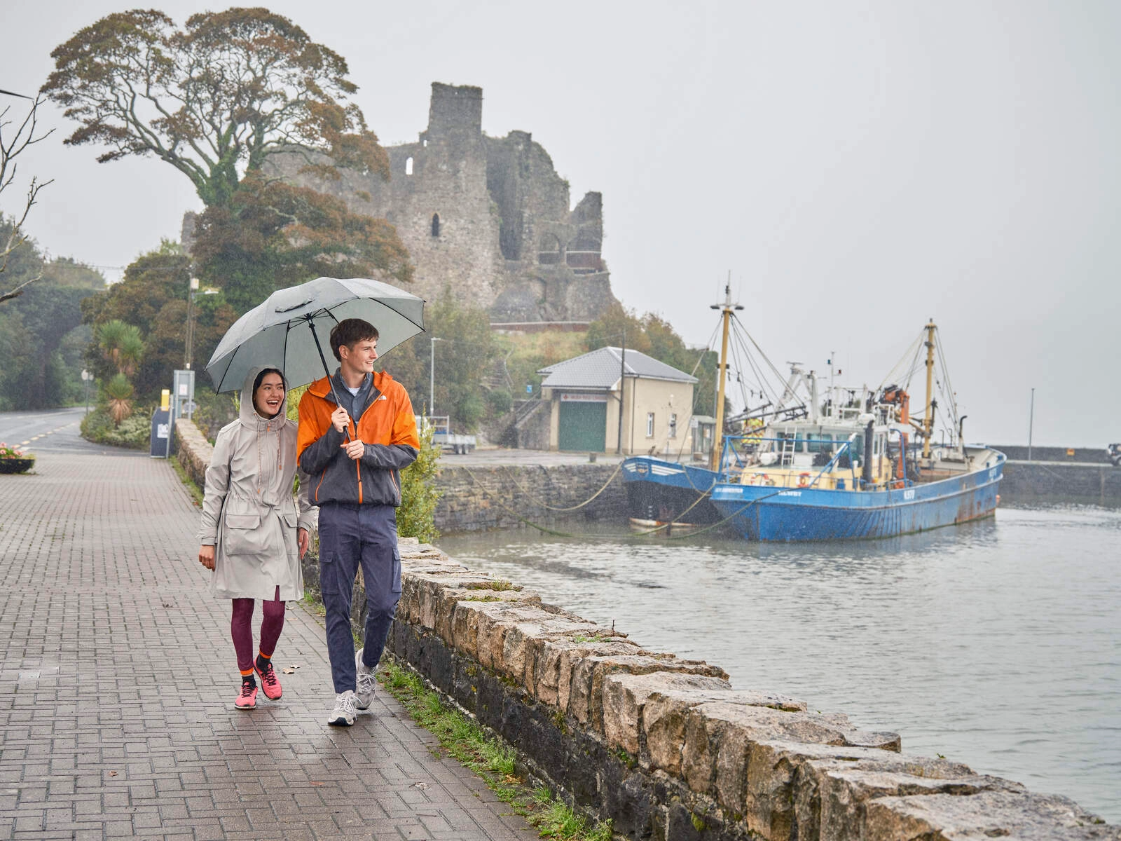 A couple walking on Omeath Pier on a wet day